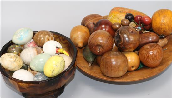 A group of egg shaped hardstone hand coolers and a group of turned and carved fruit